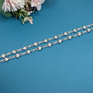 Delicate silver heart-link anklet arranged on a blue background with floral accents