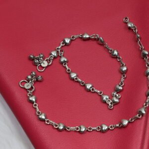 Delicate silver heart-link anklet arranged on a blue background with floral accents
