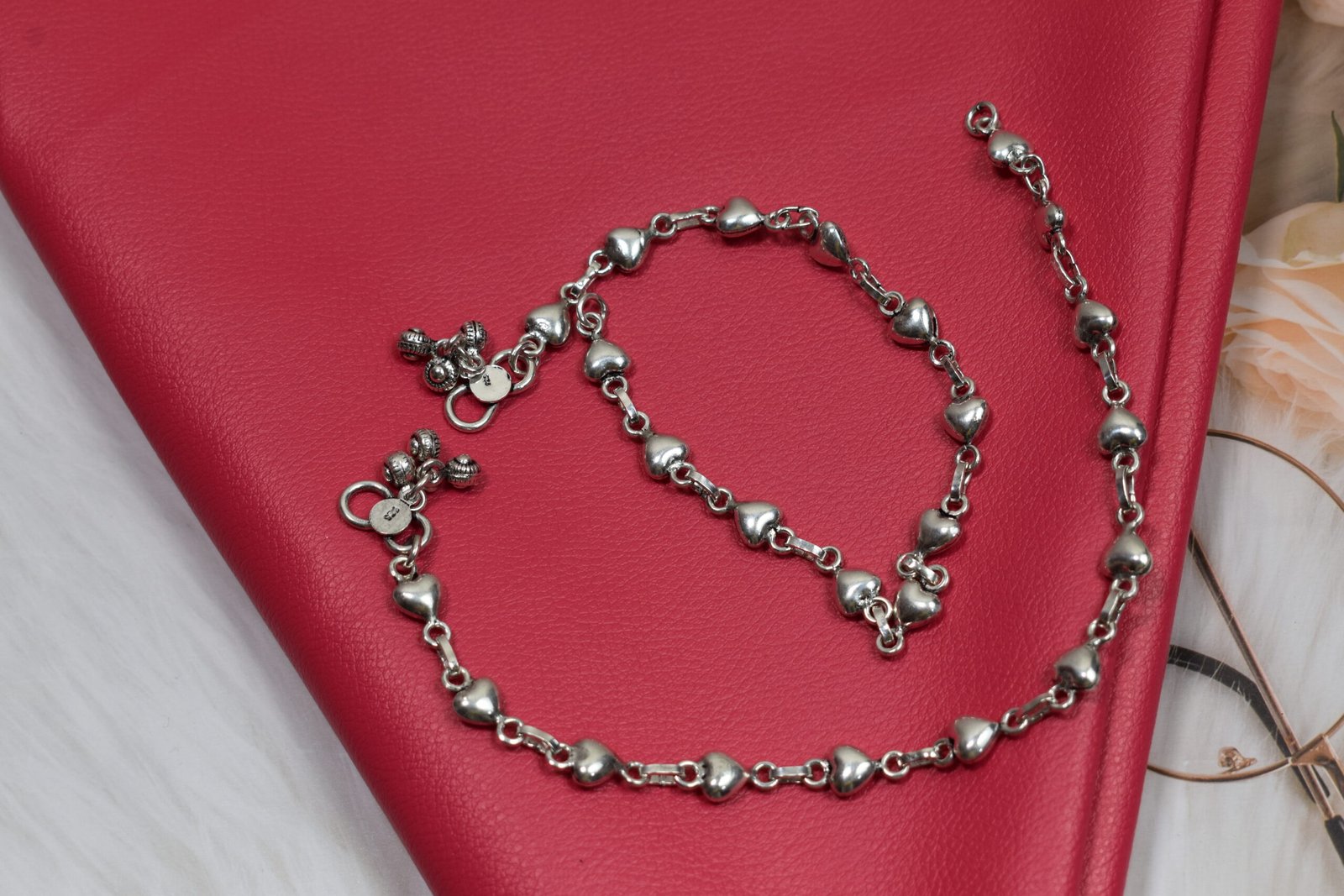 Silver Heart Link Anklet | Sukhambika 925 Atelier Delicate silver heart-link anklet arranged on a blue background with floral accents