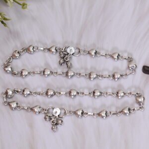 Delicate silver heart-link anklet arranged on a blue background with floral accents