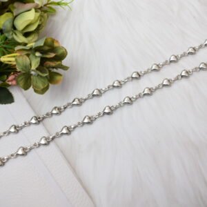 Delicate silver heart-link anklet arranged on a blue background with floral accents