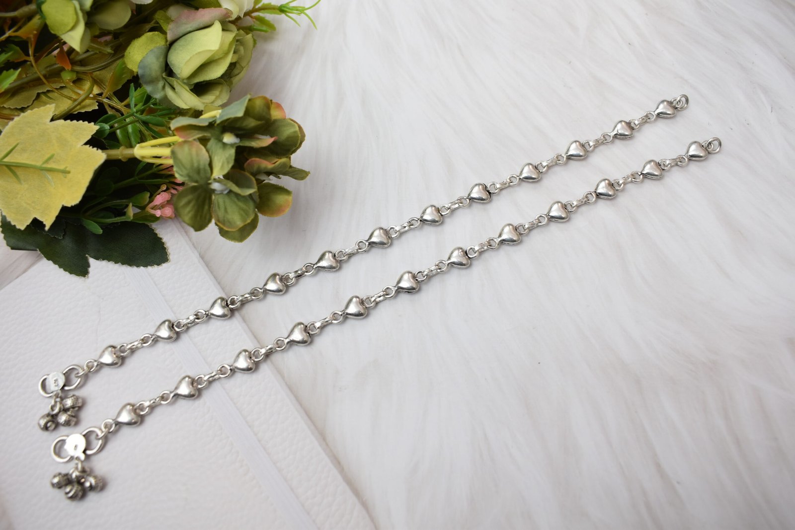 Silver Heart Link Anklet | Sukhambika 925 Atelier Delicate silver heart-link anklet arranged on a blue background with floral accents