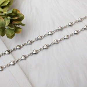 Delicate silver heart-link anklet arranged on a blue background with floral accents