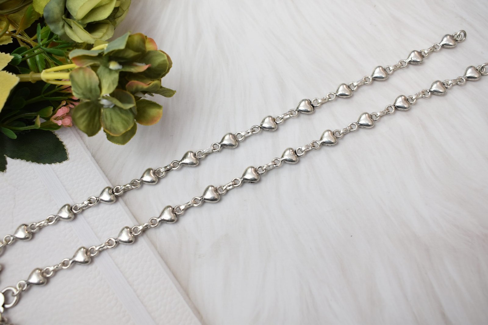 Silver Heart Link Anklet | Sukhambika 925 Atelier Delicate silver heart-link anklet arranged on a blue background with floral accents