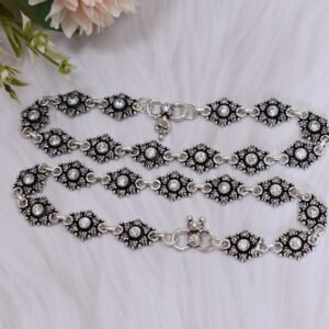 Pair of 925 sterling silver anklets coiled gracefully on a fluffy white faux fur surface, highlighting the clear center stones in oxidized floral settings and a visible 925 stamp on the S-hook clasp.