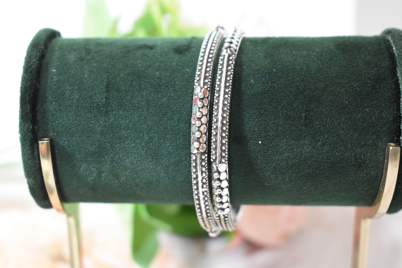 barik-dana-intricate-silver-kada2 A pair of 925 sterling silver kadas overlapping on a dark green velvet jewelry stand, showcasing an intricate barik dana (fine bead) pattern along the oxidized bands.
