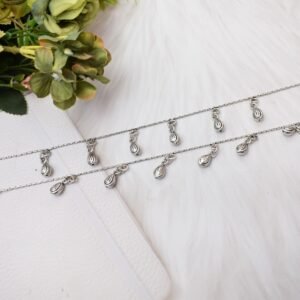 Two classic chained beads drop silver anklets resting on a white faux fur surface, showcasing the teardrop charms, an S-hook clasp with a 925 stamp, and tiny ghungroo bells