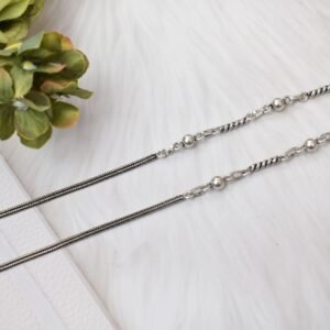 925 sterling silver anklets stretched across a white textured surface and soft faux fur, featuring a dual design with a smooth rope chain transitioning into a sequence of silver balls and twisted links, finished with a ghungroo clasp.