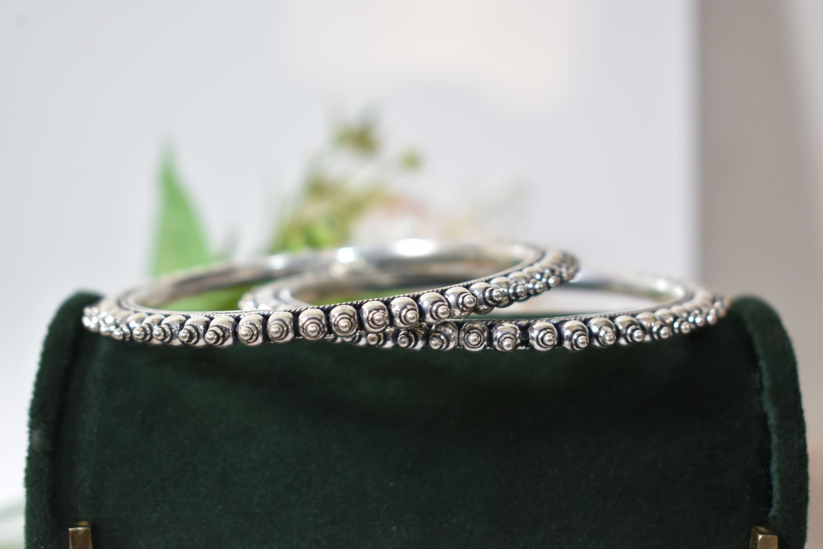 intricate-double-ball-fusion-everyday-wear-silver-kada1 A pair of overlapping 925 sterling silver kadas resting on a soft white surface, showcasing a highly textured design that fuses larger polished silver balls with a smaller beaded edge against a dark, oxidized background.
