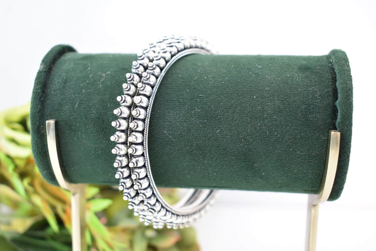 intricate-double-ball-fusion-everyday-wear-silver-kada4 A pair of overlapping 925 sterling silver kadas resting on a soft white surface, showcasing a highly textured design that fuses larger polished silver balls with a smaller beaded edge against a dark, oxidized background.