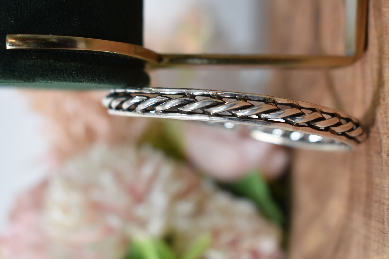 rassa-design-everyday-wear-silver-kada1 A 925 sterling silver kada featuring a traditional twisted rope or rassa design, resting horizontally on a dark green velvet jewelry stand against a soft white background.