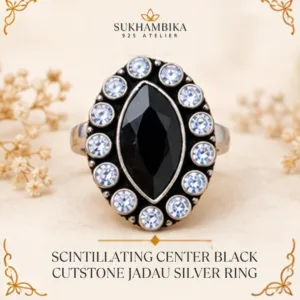 Promotional product image of the scintillating center black cutstone jadau silver ring resting on a textured light surface, featuring the Sukhambika 925 Atelier logo.