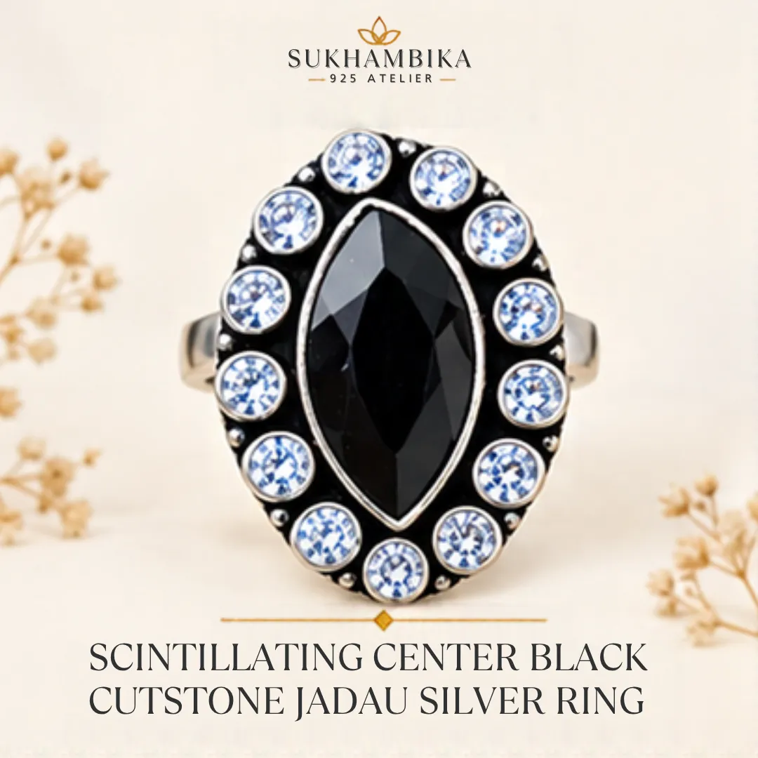 scintillating-center-black-cutstone-jadau-silver-ring-sukhambika Main promotional product image of the scintillating center black cutstone jadau silver ring resting on a textured white surface, highlighting the bold black marquise stone and classic jadau design.