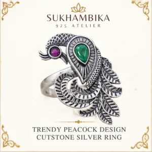 Promotional product image of the trendy peacock design cutstone silver ring resting on a textured light surface, featuring the Sukhambika 925 Atelier logo.